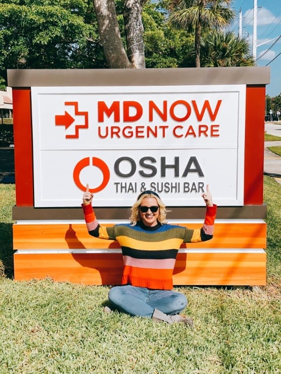 MD Now in East Boca featuring mom sitting in front of sign outside and pointing