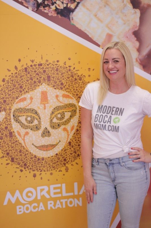 Modern Boca Mom, Michelle Olson-Rogers posing in a branded t-shirt at Morelia Gourmet Paletas in Boca Raton, FL